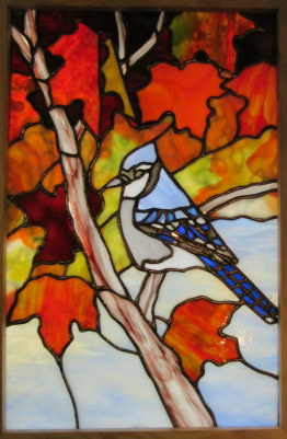 Stained glass bird blue jay in fall foliage by spectrum stained glass studio